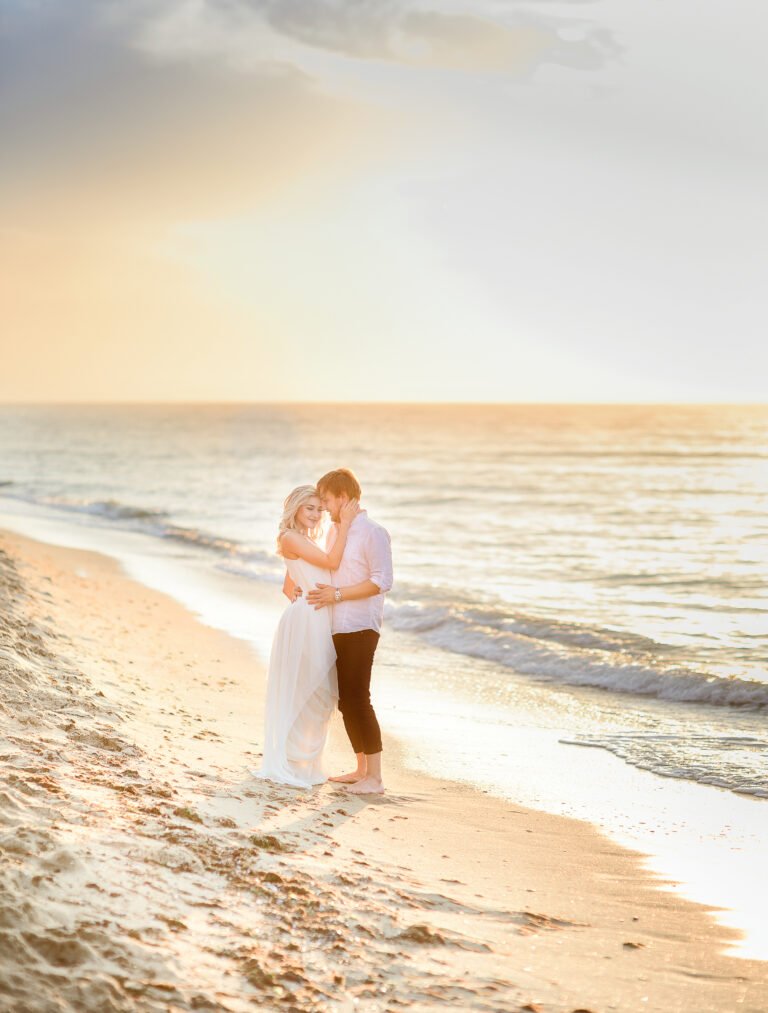 Beautiful stylish couple posing in sunlight on the beach